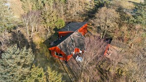 Un bâtiment rouge, doté d’un toit en pente, est entouré d’une forêt dense.