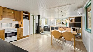 Une cuisine moderne avec des meubles en bois, un four encastré et un four à micro-ondes. On y trouve également un coin repas avec une table et des chaises en bois.