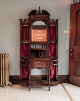 Una estantería de madera con un espejo y un letrero enmarcado que dice "THE BOOKHOUSES HOTEL".