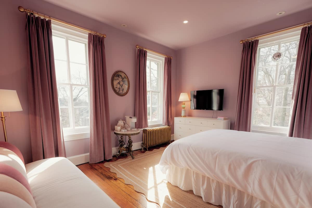 Un dormitorio con una cama grande, un aparador, un televisor y una mesa con una lámpara.
