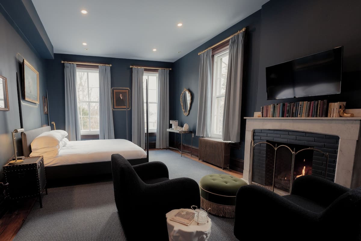 Un dormitorio moderno con una cama grande, una chimenea y un televisor instalado en la pared.