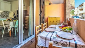 A dining area with a table set for two, a wooden cabinet, and a view of the adjacent kitchen.
