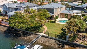 A residential area with houses, a swimming pool, and a dock with boats. - Riverside Retreat Pool, Pontoon & Space (Bundall)