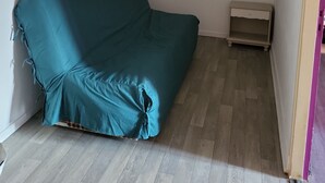 A room with a teal sofa, a small wooden nightstand, and a wooden floor. - Country house near spa  (Vandenesse)
