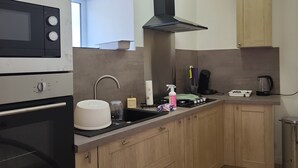 A modern kitchen with wooden cabinets, a stainless steel range hood, a microwave, and a sink. - Country house near spa  (Vandenesse)