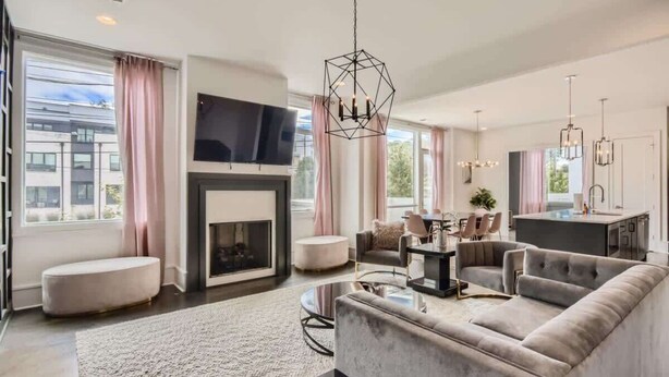 A modern living room with a fireplace, sofa, and dining area. - Songbird Suites - 2 Rooftops & Outdoor Cinema (Nashville)