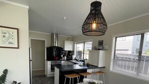 A modern kitchen with a central island, white cabinetry, and a dining area with a round table and chairs. - 3 Bdroom two-level townhouse close to Devonport  (Auckland)