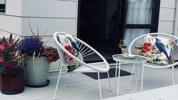 A white porch with two white wicker chairs, a small table, and a potted plant. - 3 Bdroom two-level townhouse close to Devonport  (Auckland)