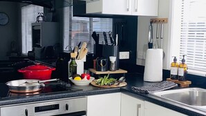 A modern kitchen with white cabinets, stainless steel appliances, and a black countertop. - 3 Bdroom two-level townhouse close to Devonport  (Auckland)