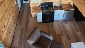 A loft-style room with a kitchen area, a dining table, and a sofa. - Charming 2-bedroom cabin with WiFi, AC 5 minutes away from Lake Guntersville (Guntersville)