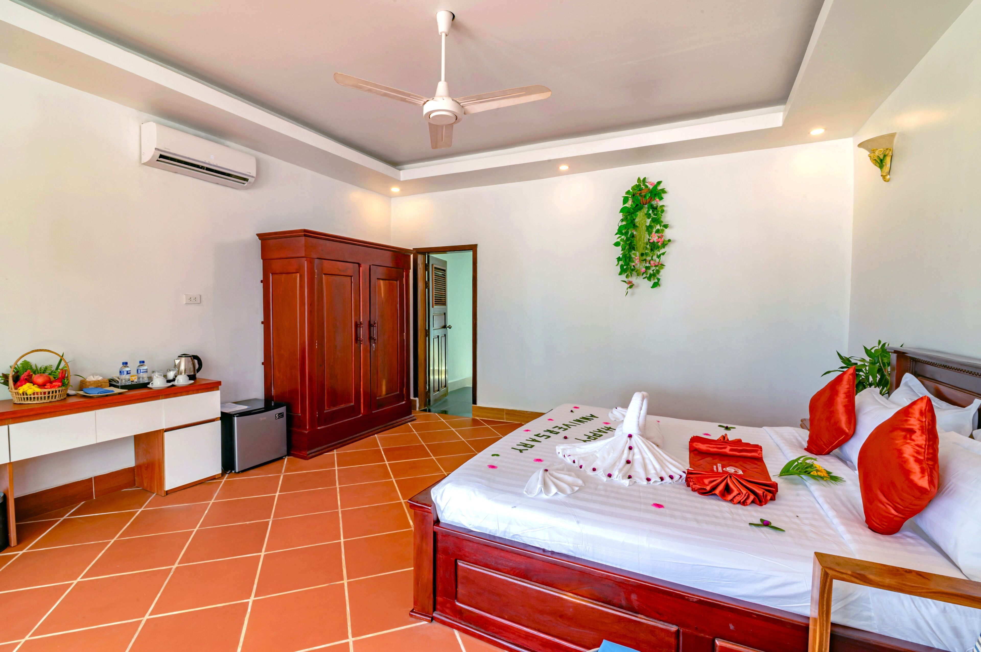 A hotel room with a bed, a desk, a wardrobe, and a ceiling fan.