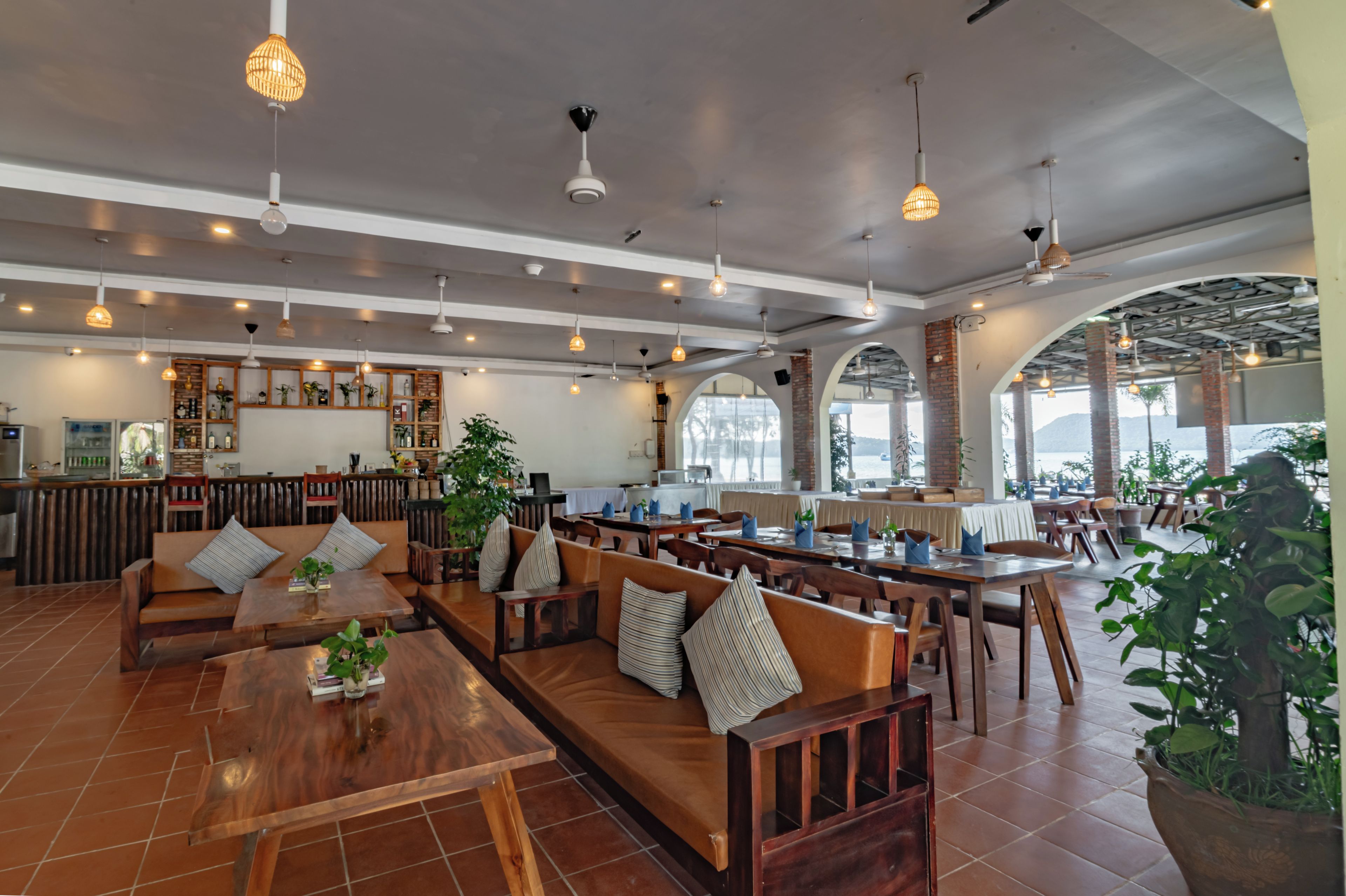 A spacious restaurant with high ceilings, multiple seating areas, and a variety of lighting fixtures.