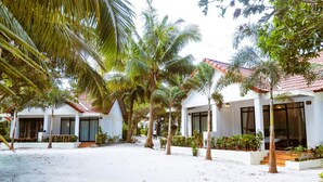 Ein Resort mit weißen Gebäuden, Palmen und einem Sandhof.