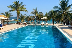 Una piscina al aire libre, sombrillas, sillones reclinables de piscina