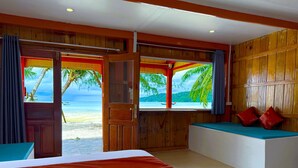 Ein Hotelzimmer mit Bett, einer Sitzbank und Blick auf Strand und Meer.