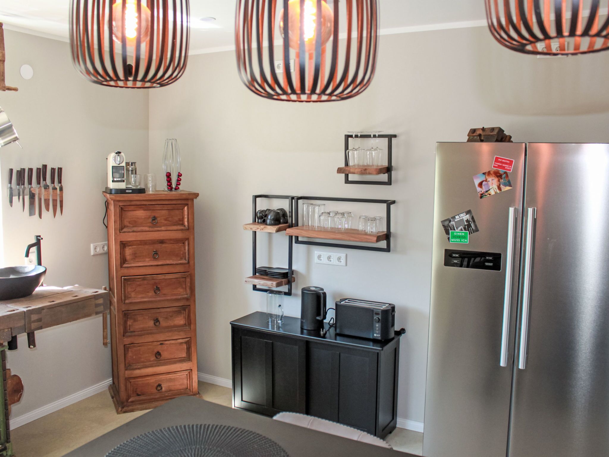 A modern kitchen with a wooden cabinet, black countertop, and a stainless steel refrigerator.