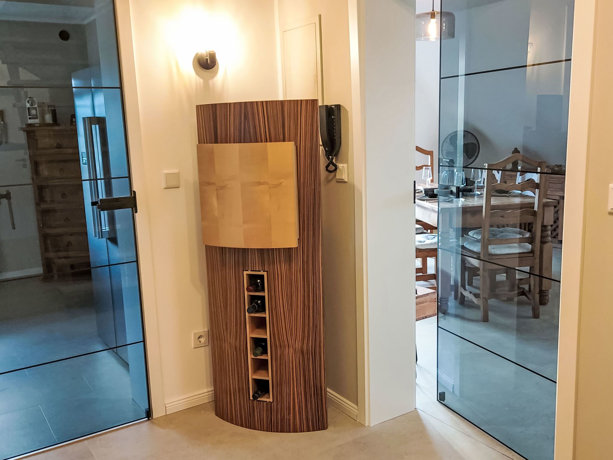 A modern kitchen with a built-in refrigerator, a wooden accent wall, and a glass partition.