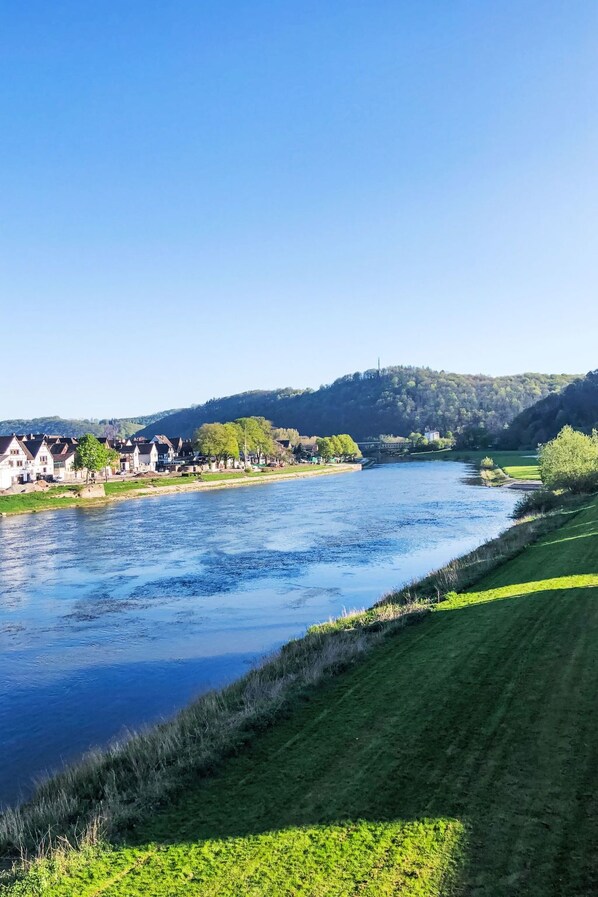 A river with houses on one bank and a grassy embankment on the other.