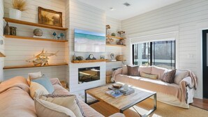 Un salon avec une cheminée, un canapé, une table basse et des objets décoratifs disposés sur des étagères.