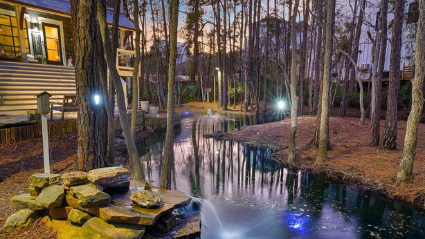 Un cadre extérieur paisible avec un étang, des arbres et un bâtiment sur lequel on peut lire l’inscription « BIENVENUE ».