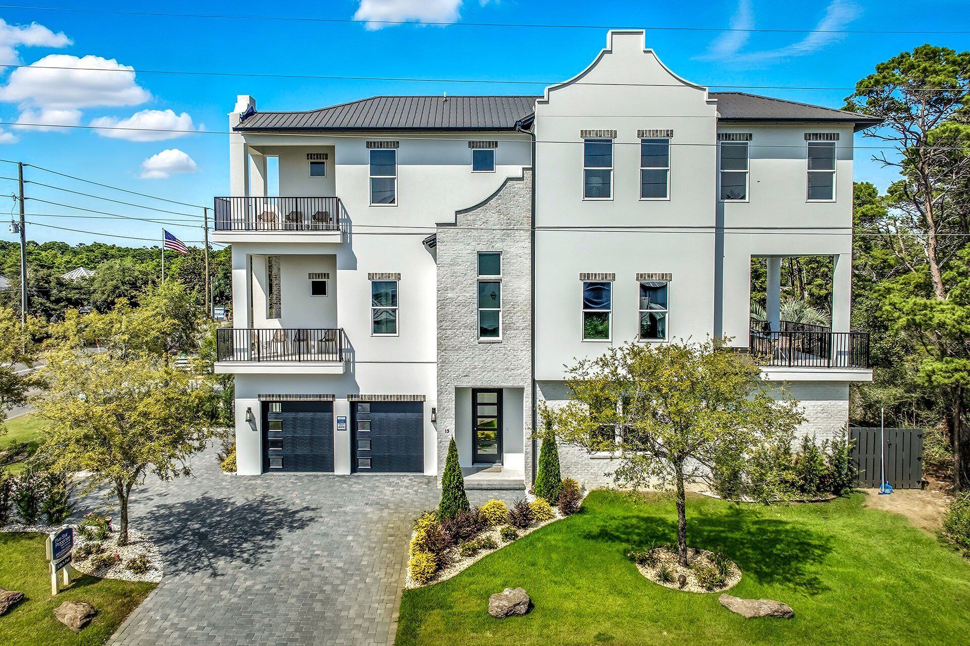 A two-story house with a modern design, featuring a balcony on the second floor, a garage, and a well-maintained lawn.