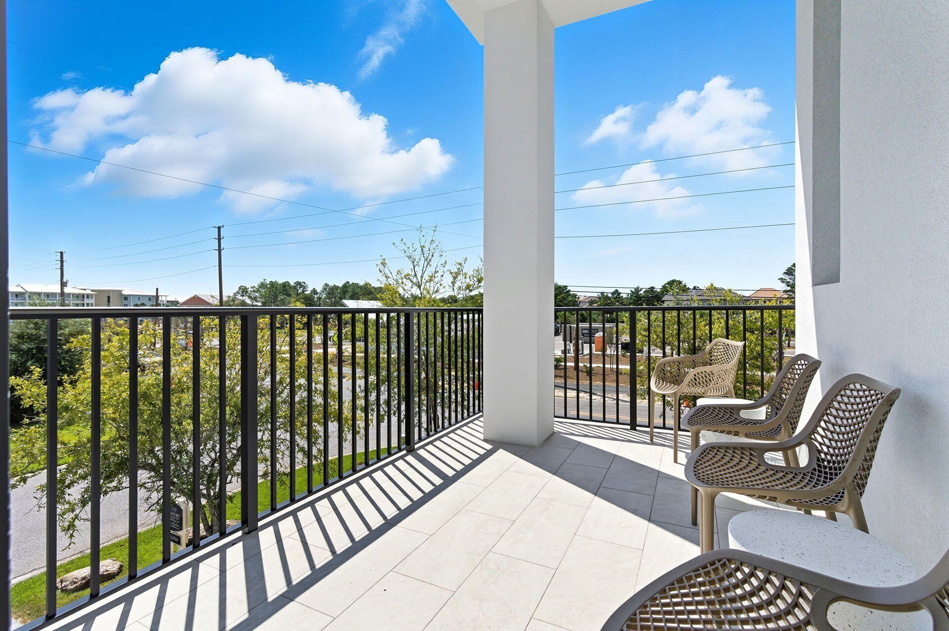 A balcony with a view of a parking lot and buildings, featuring a table and chairs.