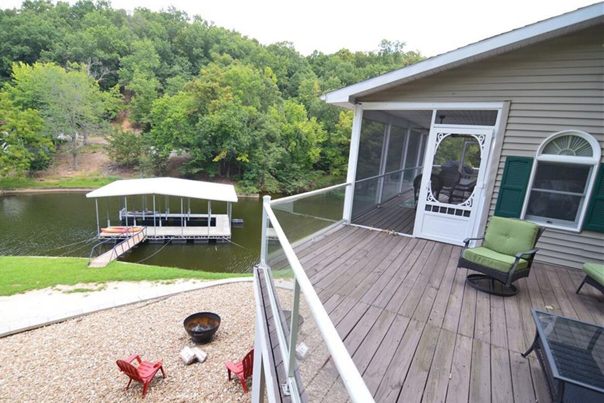 A deck with outdoor seating, a covered dock, and a lake view.