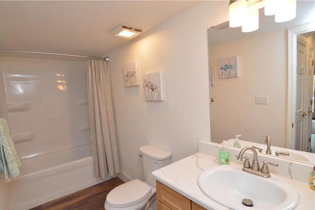 A bathroom with a bathtub, toilet, sink, and mirror.