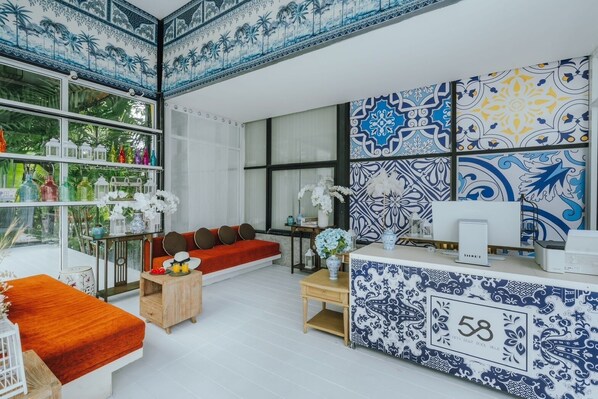A modern living room with a sofa, coffee table, and decorative items. There is a large window with a view of greenery outside. - 58 Pool Villa (Si Sunthon)