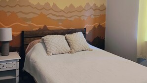 Une chambre à coucher avec un lit, une table de chevet, une lampe et un ventilateur de plafond.