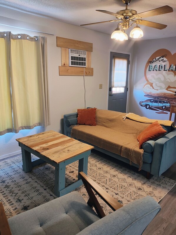 Una sala de estar acogedora con un sofá azul, una mesa de centro de madera y una alfombra estampada.