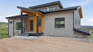 A modern two-story house with a stone facade, large windows, and a wooden porch.