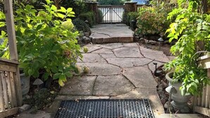 A stone pathway leading to a gated area with a pergola overhead, surrounded by autumn foliage. - Upscale Rustic Tuscan Villa with Pool in Wine Country (Petaluma)