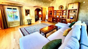 A spacious living room with a large sofa set, a coffee table, and a wooden bookshelf. - Upscale Rustic Tuscan Villa with Pool in Wine Country (Petaluma)