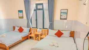 Una habitación de hotel con dos camas individuales, una silla de madera, una mesita pequeña y un espejo.