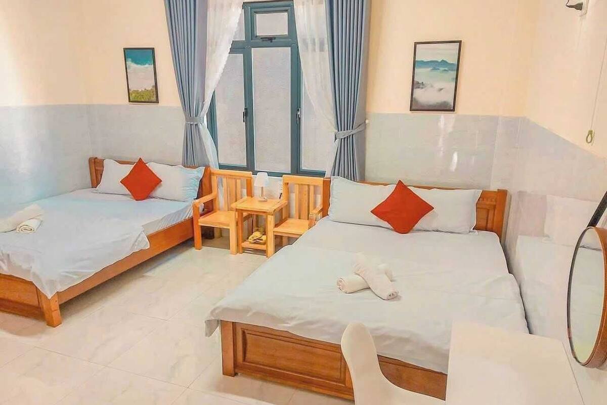 Una habitación de hotel con dos camas individuales, una silla de madera, una mesita pequeña y un espejo.