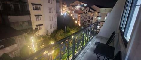 A balcony with a view of adjacent buildings at night.