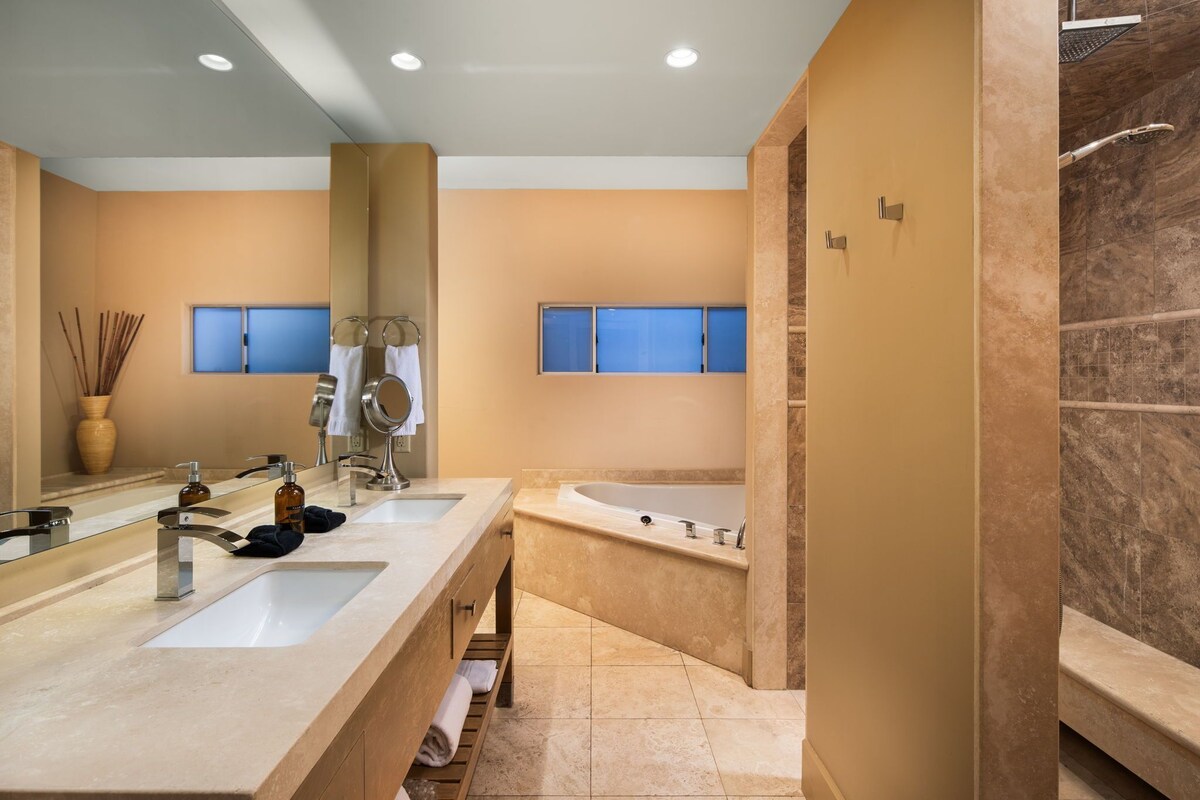 A modern bathroom with two sinks, a large bathtub, and a shower area.