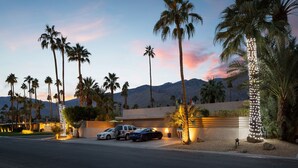 A hotel with a parking area, palm trees, and a mountain backdrop. - El Noa Noa (Palm Springs)