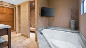 A modern bathroom with a large bathtub, a shower area, and a wooden door. - El Noa Noa (Palm Springs)