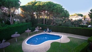 A swimming pool with a tiled deck, surrounded by a well-maintained lawn and trees. - Apartment FALCÓN by HR COSTABRAVA (Castell-Platja d'Aro)