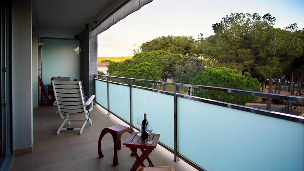 A balcony with a chair, a small table, and a bottle of wine. - Apartment FALCÓN by HR COSTABRAVA (Castell-Platja d'Aro)