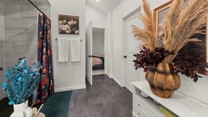 A modern bathroom with a shower, a toilet, and a sink. There is a towel rack on the wall and a decorative vase with dried plants. - Hot Tub - Game Room - FirePit - Minutes to Downtown Cleveland (Cleveland)