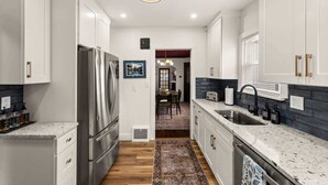 A modern kitchen with white cabinetry, stainless steel appliances, and a patterned rug.