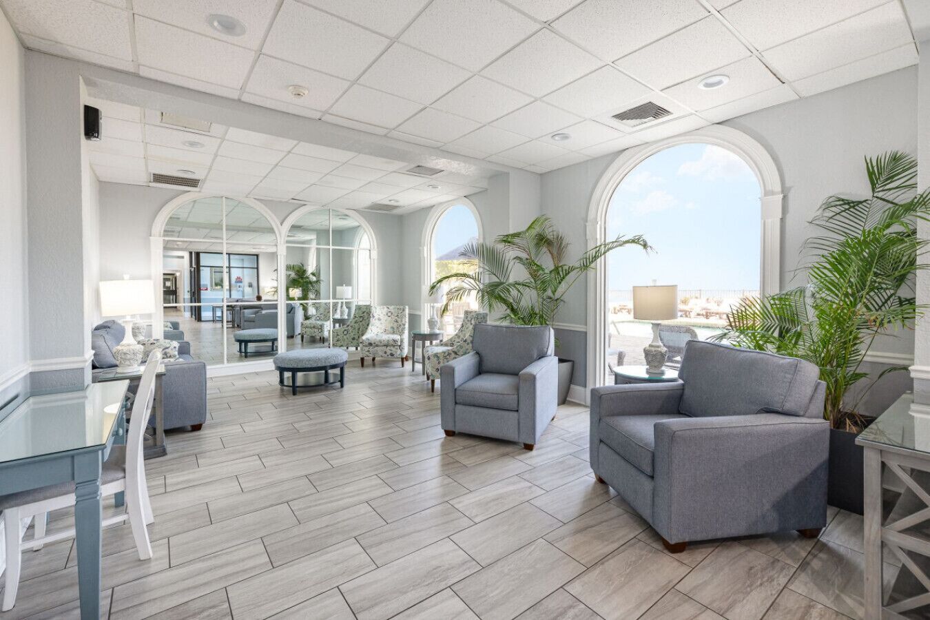 A spacious lounge area with a high ceiling, large windows, and a view of the city.