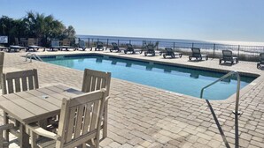 A pool area with lounge chairs and a table, overlooking a beach. - Oceanfront 2bd/2ba Amazing Views, Myrtle Beach (Myrtle Beach)