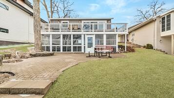 A two-story house with a balcony, a patio with a bench, and a well-maintained lawn.