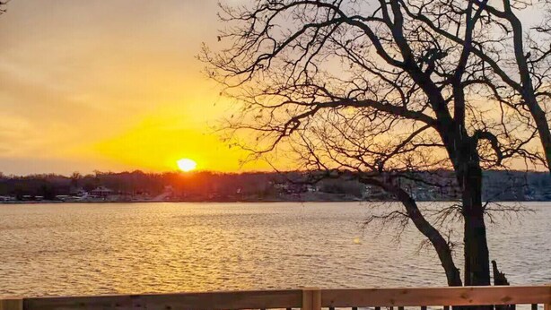 A sunset over a body of water with a wooden deck in the foreground.
