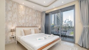 Une chambre moderne avec un grand lit, une table de chevet, une lampe, une fenêtre donnant sur la ville et un balcon avec une chaise.