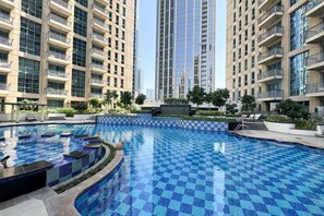 A large indoor swimming pool with a checkered tile pattern, surrounded by high-rise residential buildings.